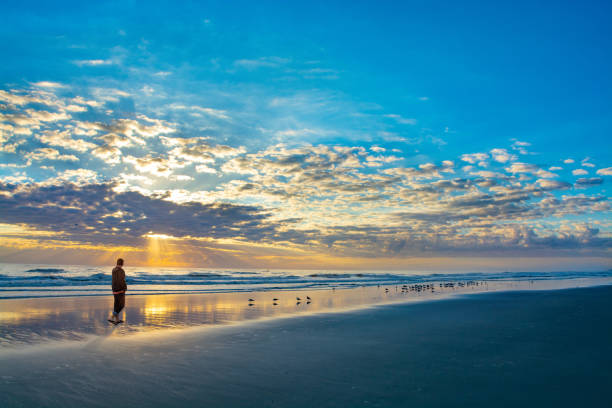 istock Man walking on beach at sunrise on summer vacation. 1158495443