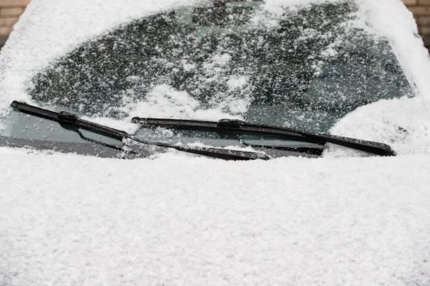 istock Car wiper blades remove snow from car windows. Snow flakes covered the car in a thick layer. Preparing for the trip in a winter, snowy day on the icy car. Safe winter driving 1158495728