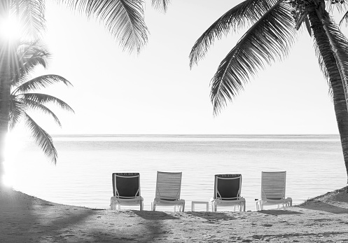 Beach holiday deckchairs in the sand overlooking the ocean in stunning black and white