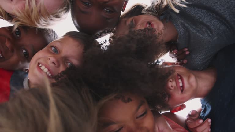 Low Angle Shot Looking Up Into Faces Of Children With Friends Smiling Into Camera