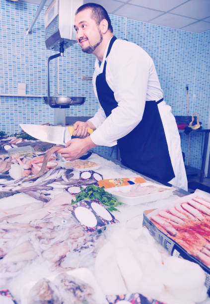 istock Man behind counter cut off piece of fish 1158498704
