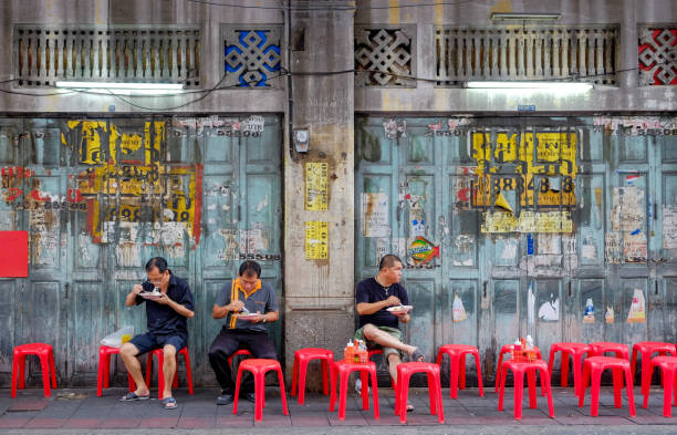 unbekannte thai-asiaten, die auf rotem stuhl sitzen, um street food zu essen - city life audio stock-fotos und bilder
