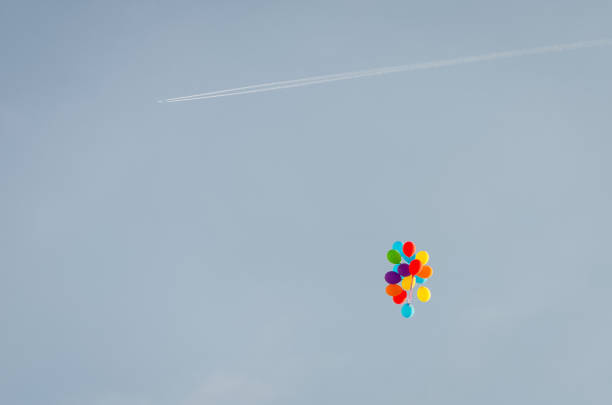 multicolor balloons and an airplane with slipstream on the blue sky with copy space - birthday airplane sky anniversary imagens e fotografias de stock