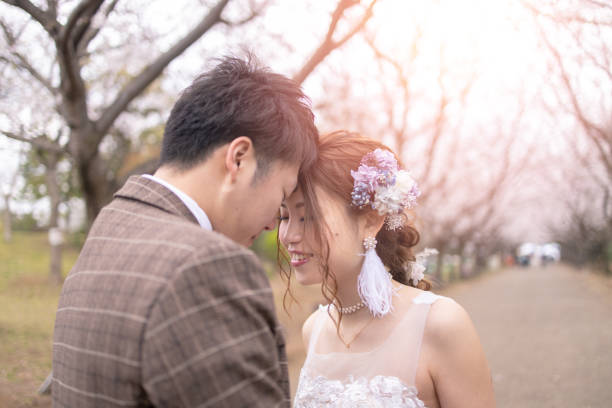 istock Bride and groom touching foreheads under cherry blossoms 1158506980