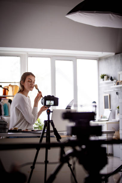istock Girl applying make up in front of camera, vlogging in studio 1158514216