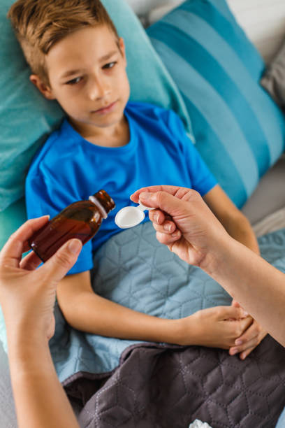 istock Mother giving son cough syrup at home 1158514310
