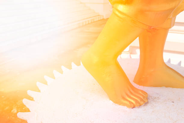 Closeup foot of golden buddha statue. Sunlight Effect.