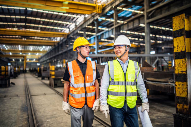 istock Two metal workers walking and talking in the factory 1158528029