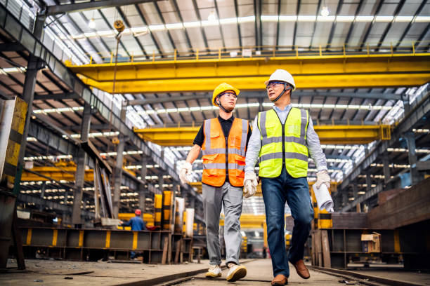 istock Two metal workers walking and talking in the factory 1158528173