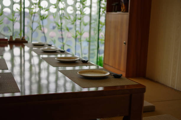 Empty japanese cuisine restaurant tatami table setting with chopsticks and plates and bamboo near window as decoration Empty japanese cuisine restaurant tatami table setting with chopsticks and plates and bamboo near window as decoration washoku stock pictures, royalty-free photos & images