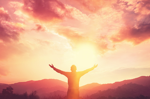 Copy space of man hand raising on top of mountain and sunset sky abstract background. Freedom travel adventure and business victory concept. Vintage tone filter effect color style.