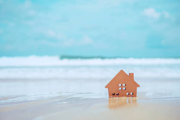 cerrado pequeños modelos caseros en arena con luz solar y fondo de playa. - tangram casa fotografías e imágenes de stock