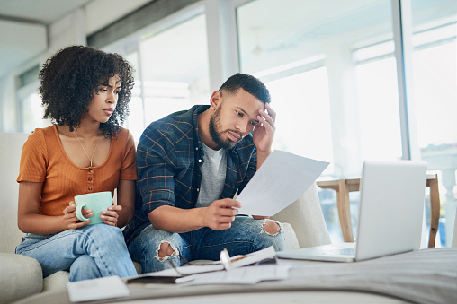 Shot of a young couple looking stressed while going over their finances at home