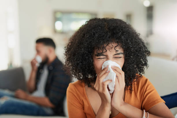 кто пригласил этих микробов гриппа на вечеринку? - sneezing tissue young adult cold стоковые фото и изображения