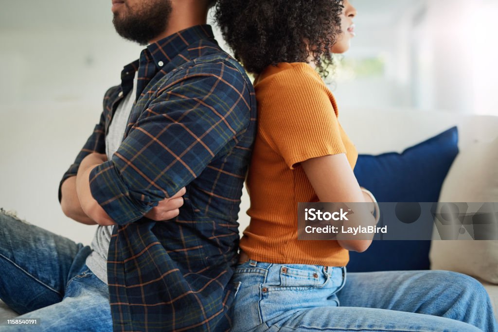 They've turned their backs on constructive communication Shot of a young couple having a disagreement at home Couple - Relationship Stock Photo