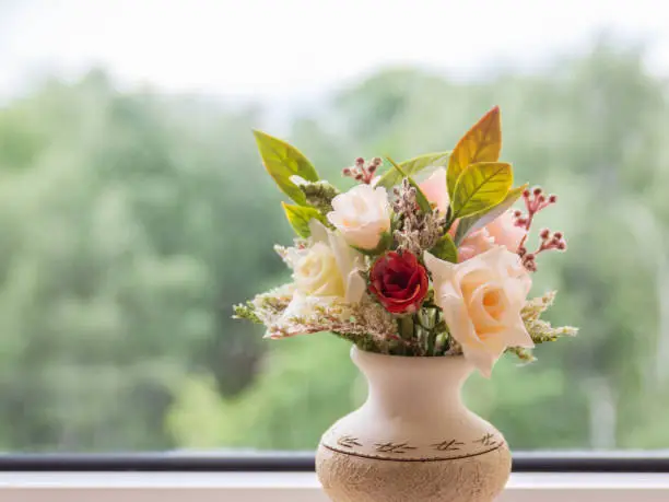 Vase of flowers on the background of an open window with a summer landscape