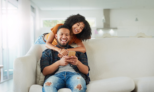 Shot of a young couple using a smartphone while relaxing together at home