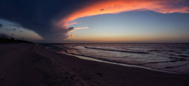 Beautiful panoramic view of the sandy beach during a dramatic cloudy sunset. Taken in Varadero, Cuba.