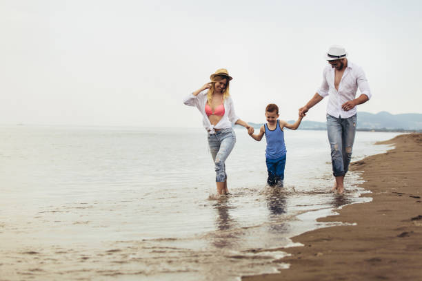 istock Parents Walking Along Beach With Child On Summer Vacation 1158549435