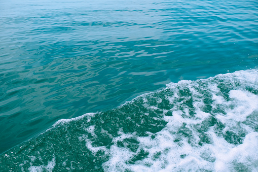 Ocean waves and sea foam caused by the sail of a speed boat