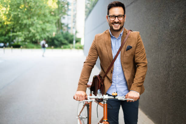felice giovane uomo d'affari elegante andando a lavorare in bicicletta - ethnicity cycle professional occupation business person foto e immagini stock