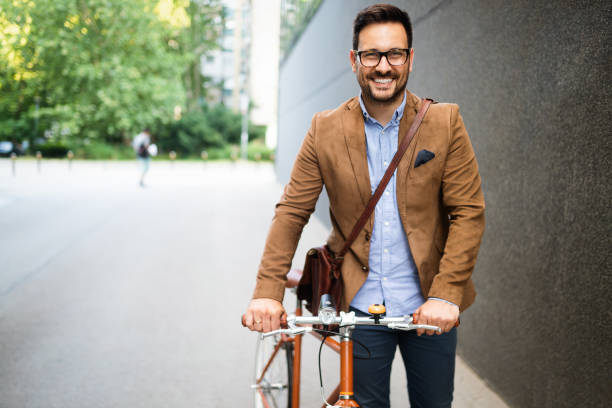 happy young stylish businessman going to work by bike - cycling cyclist bicycle men imagens e fotografias de stock