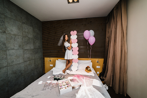 Woman with pink air balloons on bachelorette party. Beautiful sexy young girl in dress and veil on bachelor party. Maiden evening, Hen-parties. Place for text.