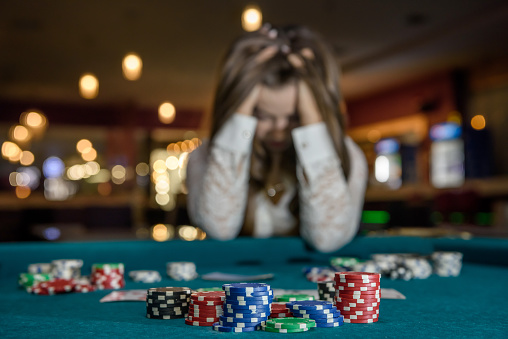 Mujer molesta en el casino sentado detrás de la mesa de póquer photo