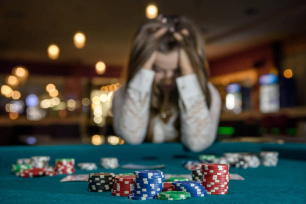 Upset woman in casino sitting behind poker table stock photo