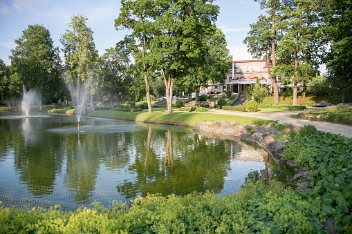 City Cesis, Latvian republic. Pond with fountain in city park. Everything is blossoming and green around. 22.06.2019.