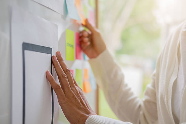 istock Web designer brainstorming for a strategy plan. Colorful sticky notes with things to do on office board. User experience (UX) concept. 1158557881