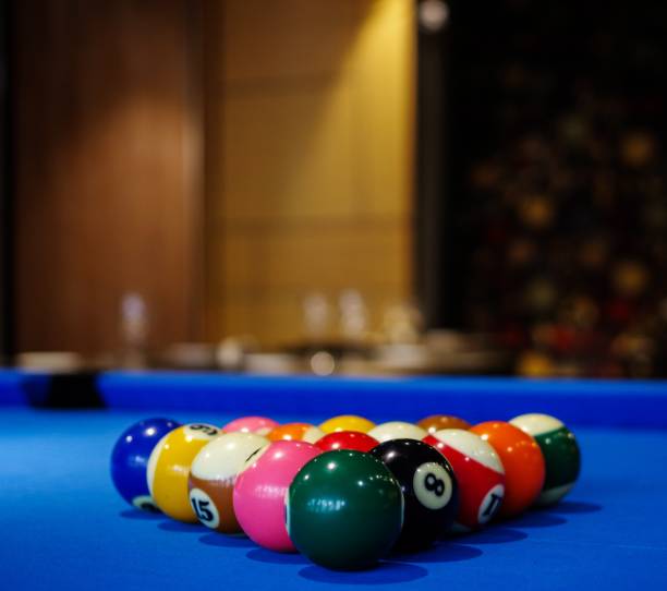 istock Blue pool table and billiard balls set up. Restaurant tables with wineglasses as background 1158558037
