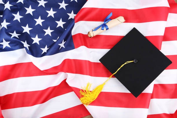 istock Graduation cap with diploma on American flag background 1158558814