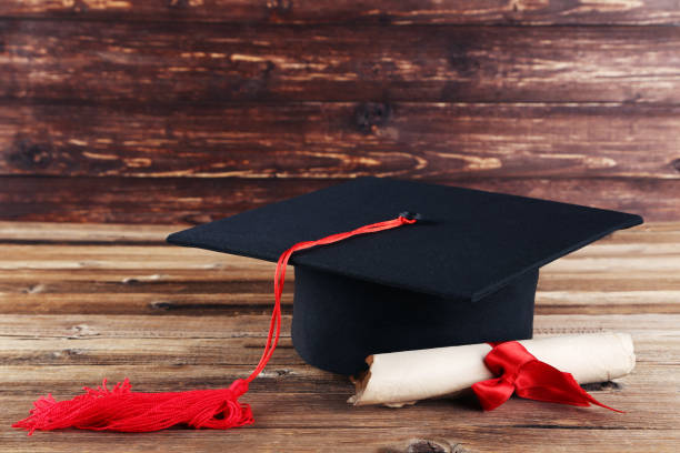 istock Graduation cap with diploma on brown wooden table 1158558820