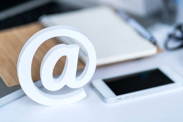 istock Email comcept. Contact us for feedback. Desktop with notepad, smartphone, glasses and email symbol. Top view 1158560132