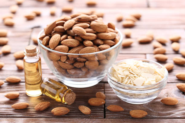Almond and oil in bottles on brown wooden table stock photo