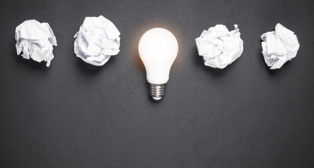 istock Light bulb and crumpled papers in the black background. Idea 1158568672