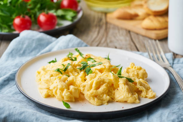 istock Scrambled eggs, omelette, close up. Breakfast with pan-fried eggs, cup of tea, tomatoes on old wooden table 1158571552