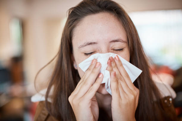 istock Young woman with cold or flu blows her nose on a tissue 1158571823
