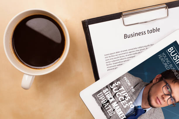 istock Tablet pc showing magazine on screen with a cup of coffee on a desk 1158573193