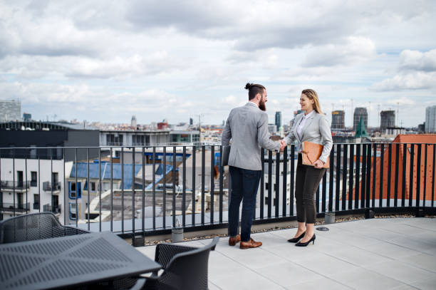 istock Two young business people standing on a terrace outside office, shaking hands. 1158574578