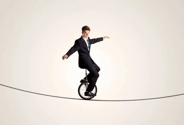 Photo of Extreme business man riding unicycle on a rope