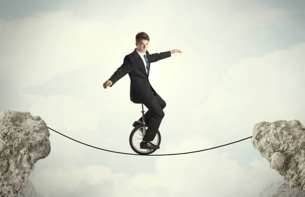 istock Brave business man riding an mono cycle between cliffs 1158574826
