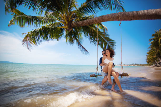 Beautiful happy couple on swing on tropical beach, honeymoon vacation concept Beautiful happy couple on swing tropical beach, honeymoon vacation concept honeymoon stock pictures, royalty-free photos & images