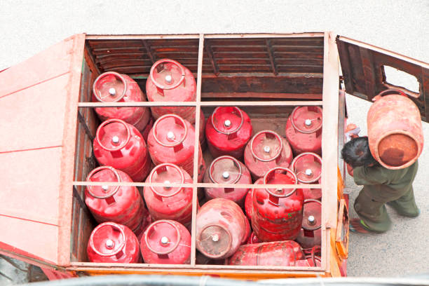 Van having LPG cylinder and a worker distributing a cylinder in a residental area Van having LPG cylinder and a worker distributing a cylinder in a residental area liquefied petroleum gas photos stock pictures, royalty-free photos & images