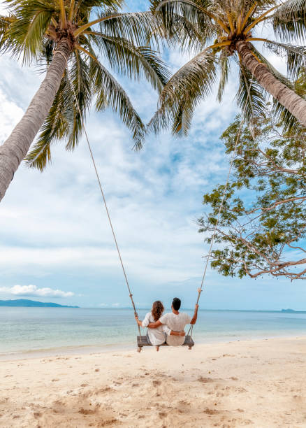 Young couple swinging on a swing on paradise tropical beach honeymoon, vacation, travel concept Young couple swinging on a swing on paradise tropical beach, honeymoon, vacation, travel concept honeymoon beach stock pictures, royalty-free photos & images