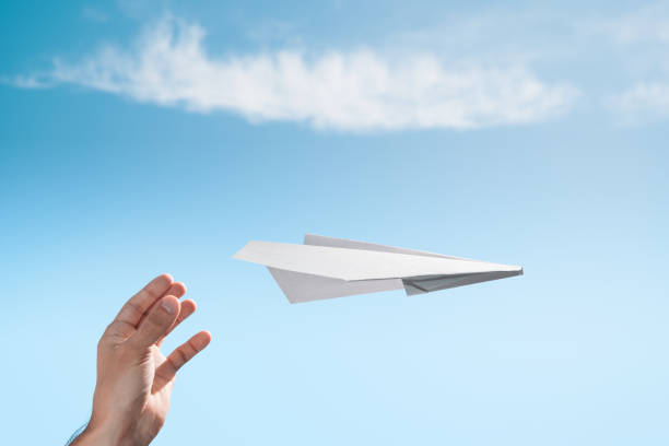 the launch of a paper plane in free flight. male hand. - artificial wing fotos imagens e fotografias de stock