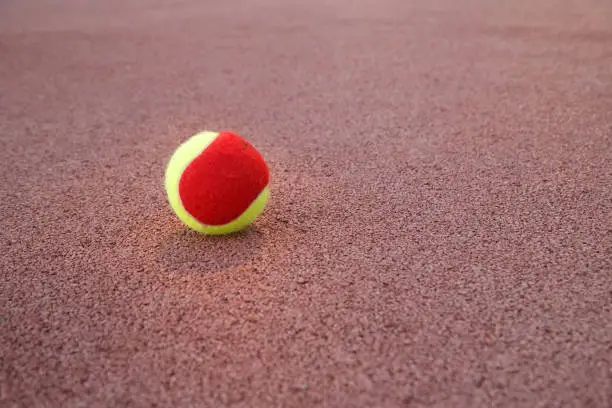 yellow-red tennis ball on the tennis court in the evening
