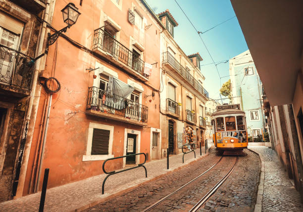 tranvía coche pasando por la calle de casas antiguas en la capital - cable car lisbon portugal portugal old fotografías e imágenes de stock
