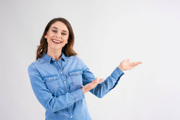 istock Smiling, young woman pointing at copy space at studio shot 1158597303